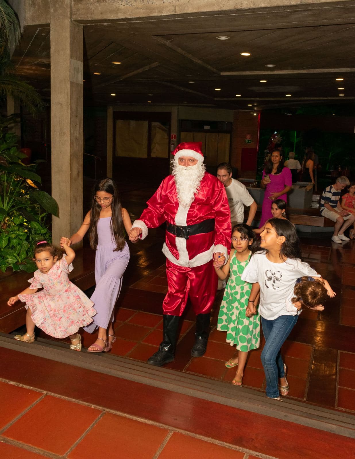 Chegada do Papai Noel ao lobby do hotel, recebido por crianças hospedadas