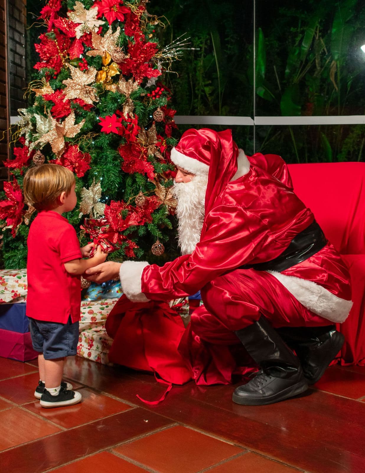 Papai Noel entregando um presente a uma criança durante a festa de Natal